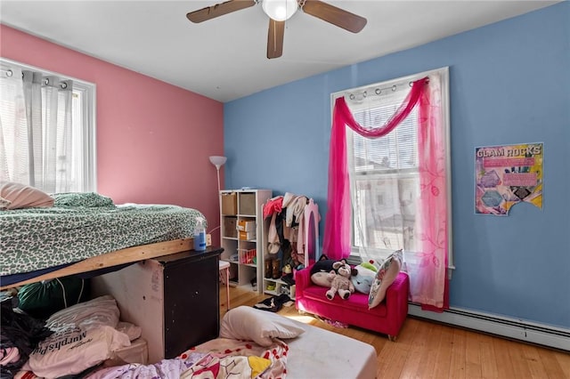 bedroom with wood finished floors, a ceiling fan, and a baseboard radiator