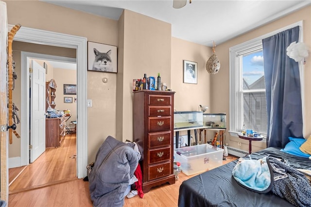 bedroom featuring a baseboard heating unit and wood finished floors