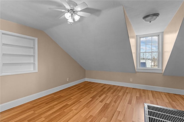 bonus room featuring visible vents, built in shelves, baseboards, and wood finished floors