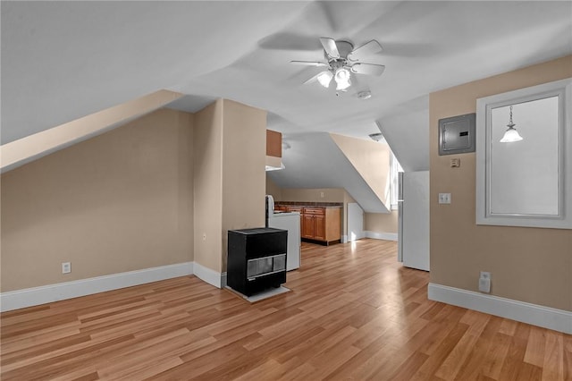 additional living space with electric panel, light wood-type flooring, baseboards, and vaulted ceiling