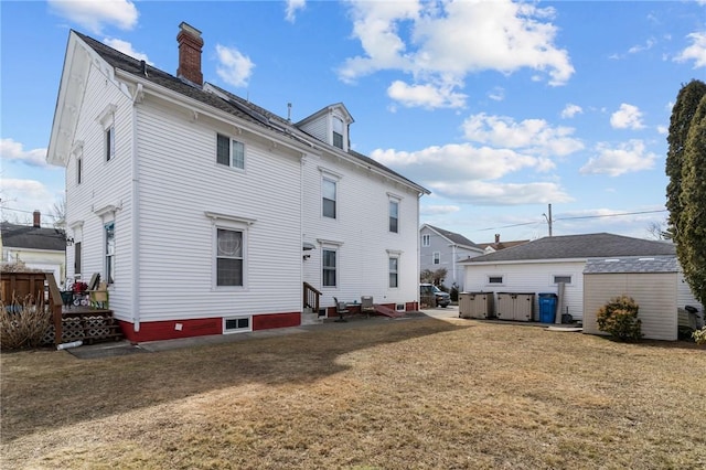 back of house with a hot tub, entry steps, a chimney, and a yard