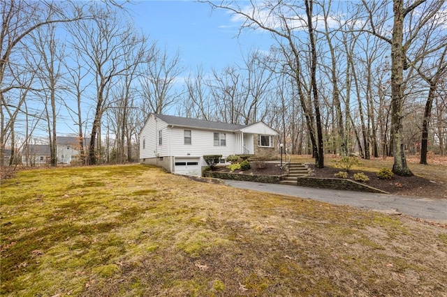 exterior space featuring driveway, an attached garage, and a front yard