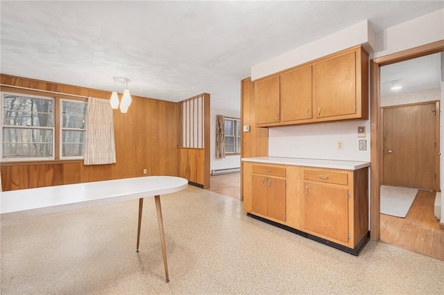 kitchen featuring wooden walls, light floors, light countertops, brown cabinets, and baseboard heating