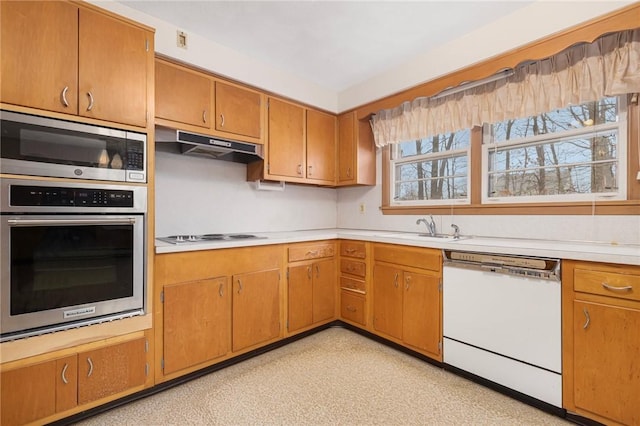 kitchen featuring white dishwasher, a sink, light countertops, electric cooktop, and under cabinet range hood