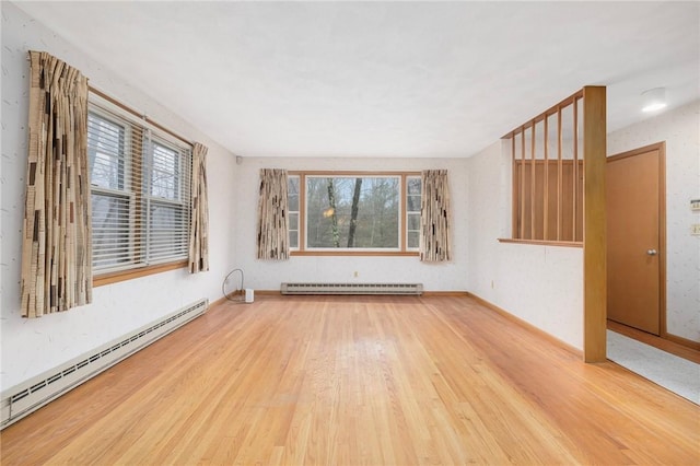 empty room featuring a wealth of natural light, a baseboard heating unit, wood finished floors, and a baseboard radiator