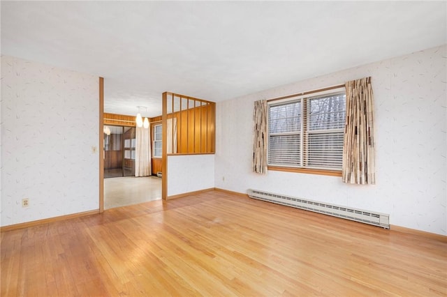 unfurnished room featuring light wood finished floors, a baseboard heating unit, and baseboards