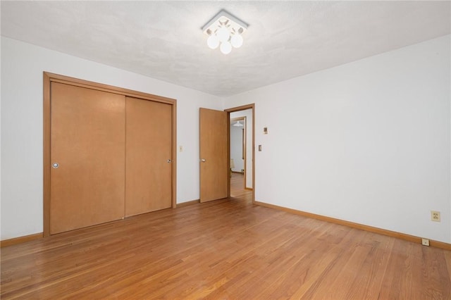 unfurnished bedroom with light wood finished floors, baseboards, and a closet