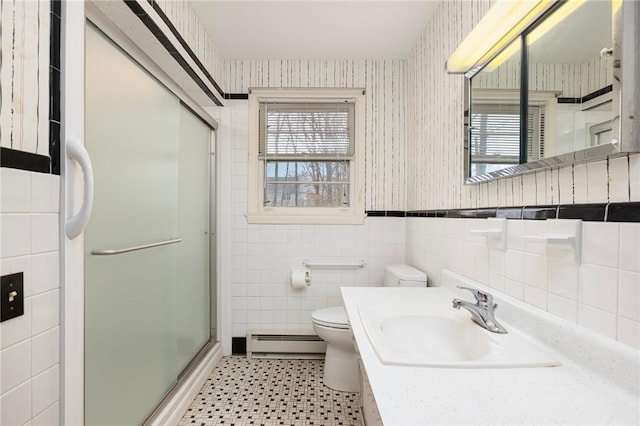 bathroom featuring wallpapered walls, a stall shower, a baseboard heating unit, tile walls, and toilet