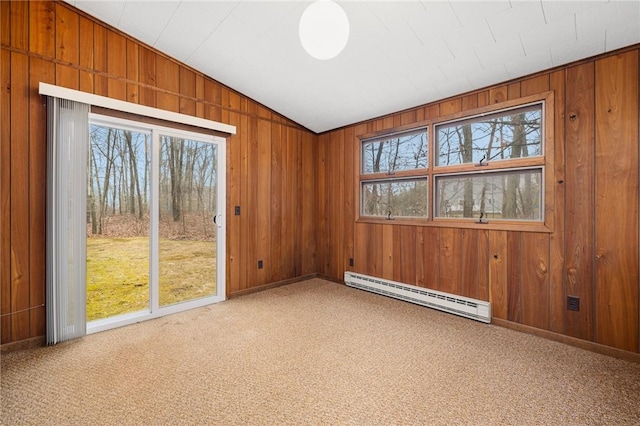 carpeted empty room with a baseboard heating unit, lofted ceiling, wooden walls, and baseboards