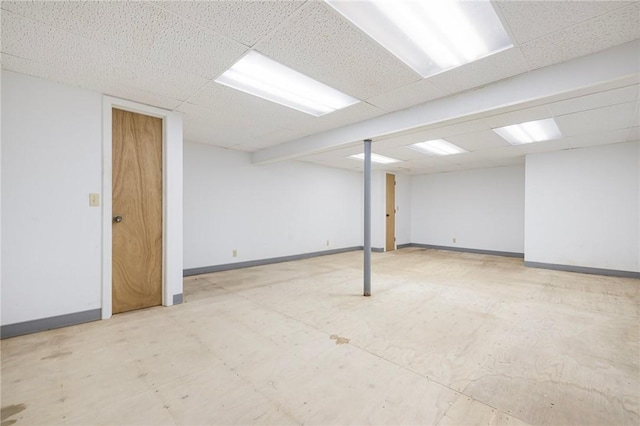 finished basement with tile patterned floors, a drop ceiling, and baseboards