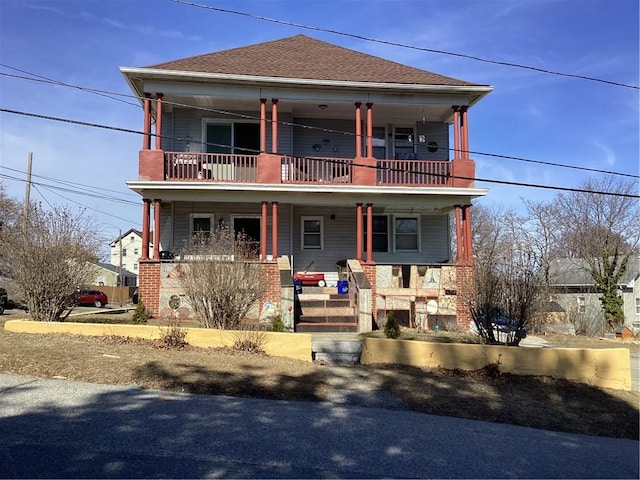 view of front facade featuring a balcony, covered porch, and a shingled roof