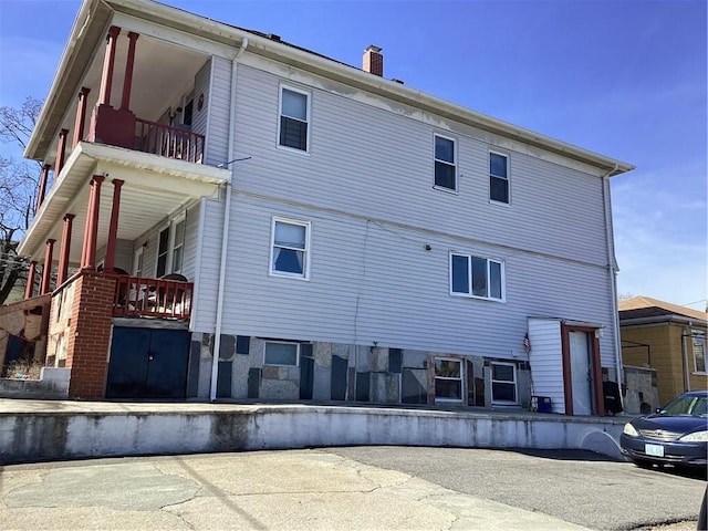 rear view of property featuring a balcony and a chimney