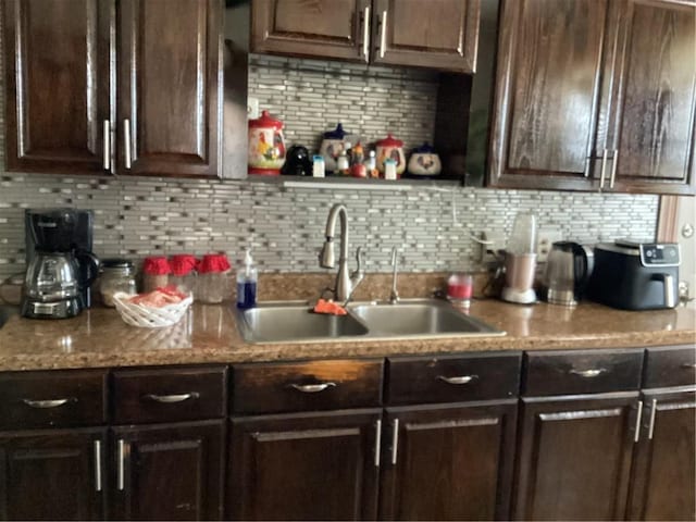 kitchen featuring a sink, decorative backsplash, and dark brown cabinets