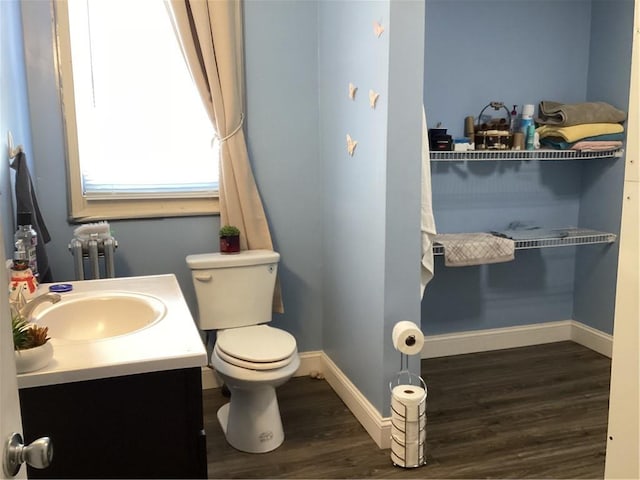 bathroom featuring baseboards, toilet, radiator heating unit, wood finished floors, and vanity