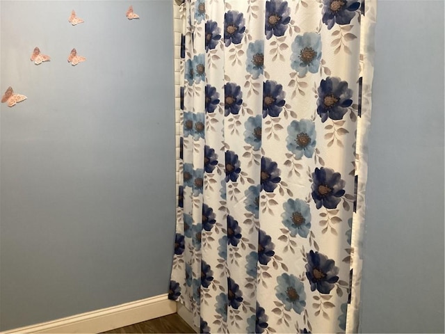 details with a shower with shower curtain and baseboards