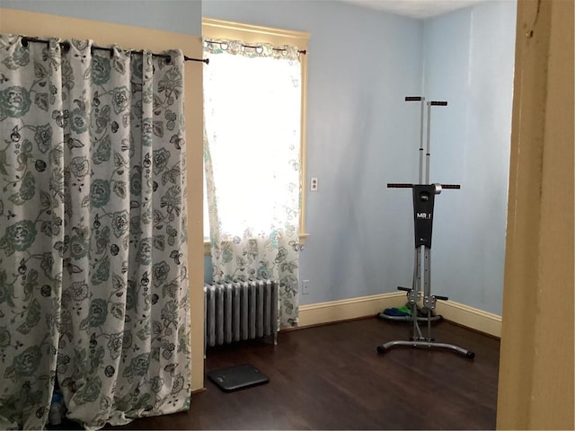 workout room with baseboards, radiator, and wood finished floors