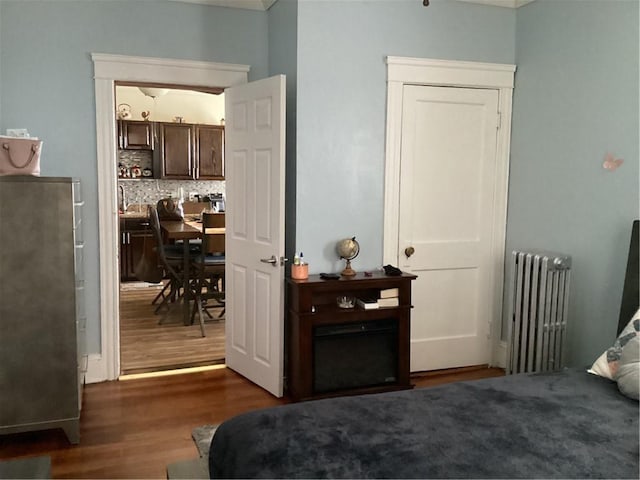 bedroom with radiator and wood finished floors