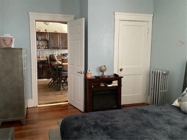 bedroom with radiator heating unit and wood finished floors