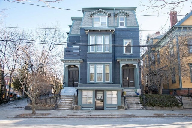 second empire-style home featuring mansard roof and a balcony