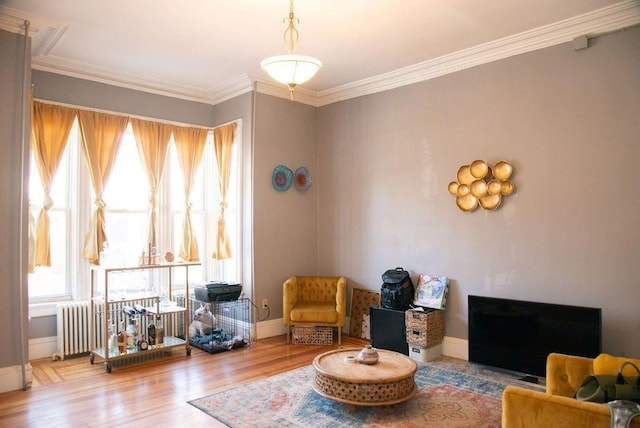 sitting room featuring baseboards, wood finished floors, radiator heating unit, and crown molding