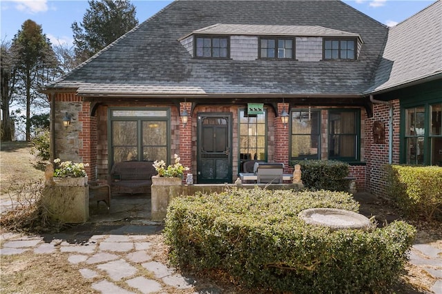 view of front of house with brick siding and a shingled roof