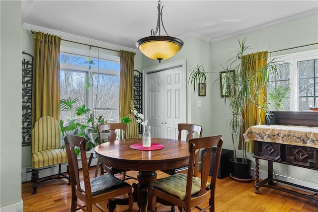 dining space featuring light wood-style flooring, a baseboard radiator, and ornamental molding