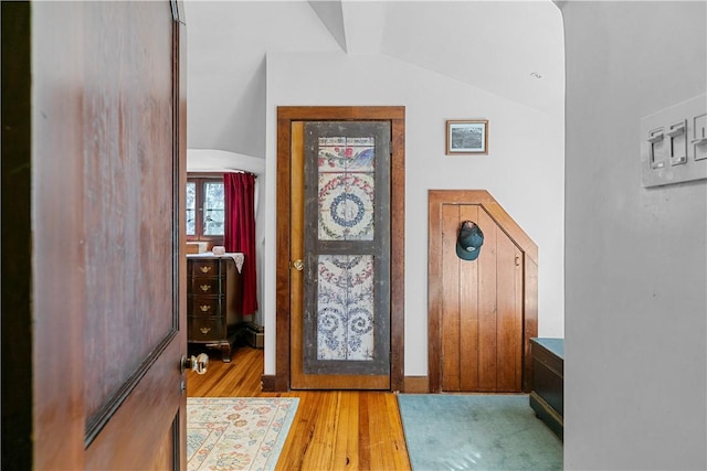 entryway featuring arched walkways, lofted ceiling, and wood finished floors