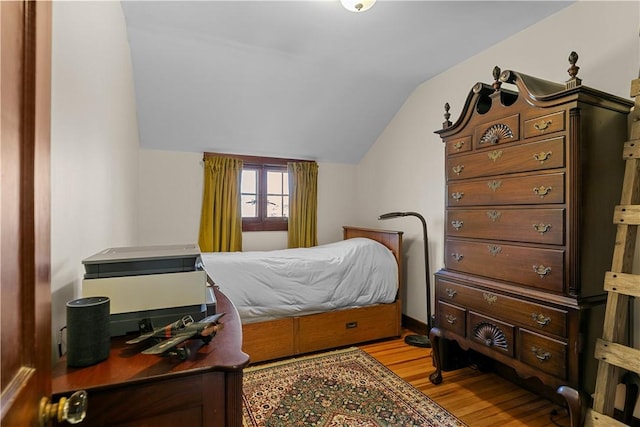 bedroom with light wood finished floors and lofted ceiling