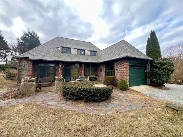 view of front of property with driveway, brick siding, a garage, and roof with shingles