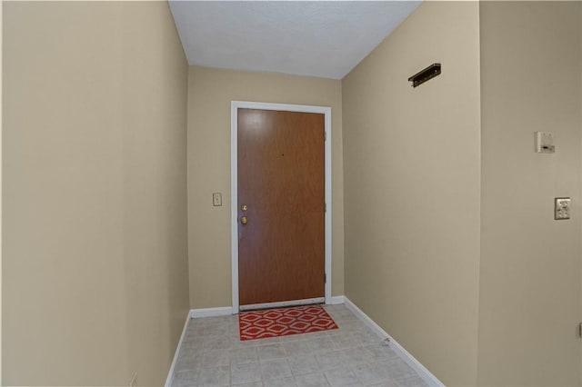 doorway featuring baseboards and light floors