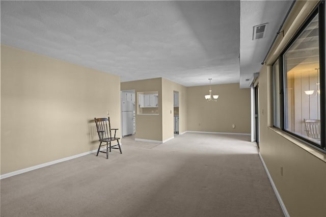 unfurnished room featuring light carpet, visible vents, baseboards, and a notable chandelier