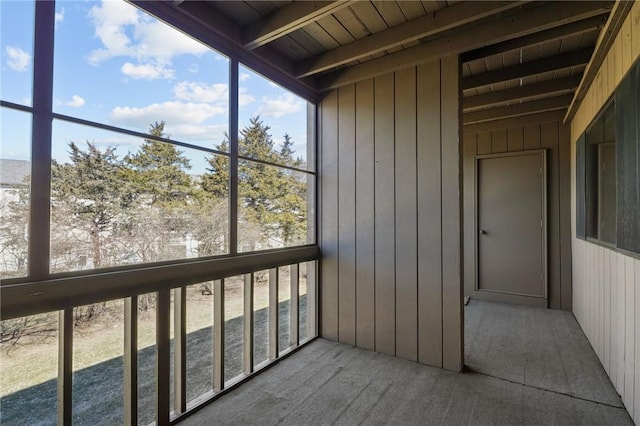 unfurnished sunroom featuring beamed ceiling and wooden ceiling