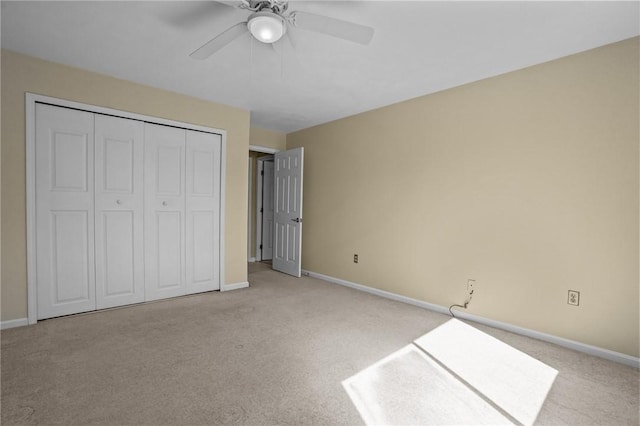 unfurnished bedroom with light carpet, a closet, baseboards, and a ceiling fan