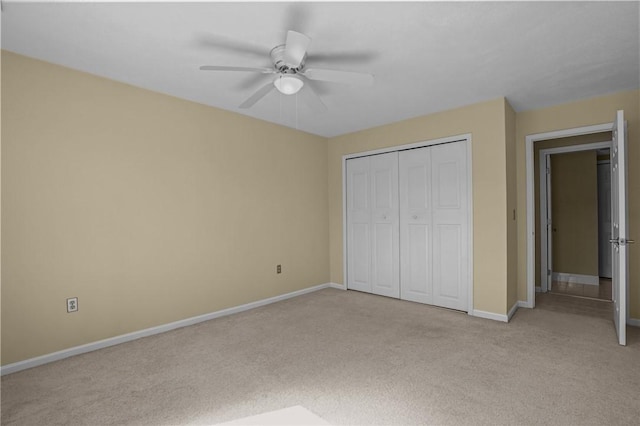 unfurnished bedroom featuring a closet, baseboards, light colored carpet, and ceiling fan