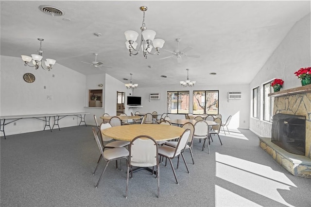 carpeted dining space with visible vents, ceiling fan with notable chandelier, a stone fireplace, and vaulted ceiling