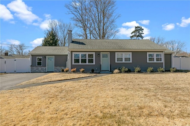 single story home featuring a front lawn, fence, a chimney, stone siding, and a gate