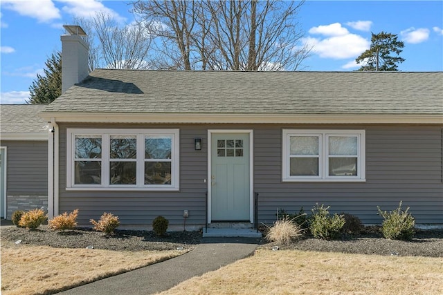 bungalow-style house featuring roof with shingles and a chimney