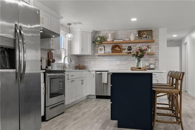 kitchen with under cabinet range hood, tasteful backsplash, appliances with stainless steel finishes, and light countertops