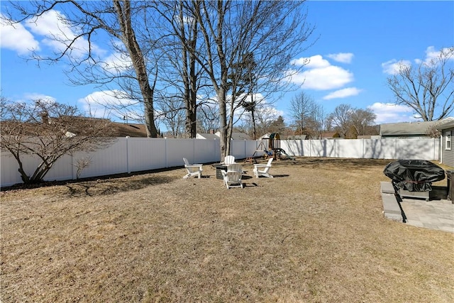 view of yard featuring a patio area, a playground, and a fenced backyard