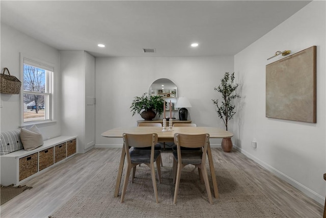 dining area featuring light wood-type flooring, visible vents, recessed lighting, arched walkways, and baseboards