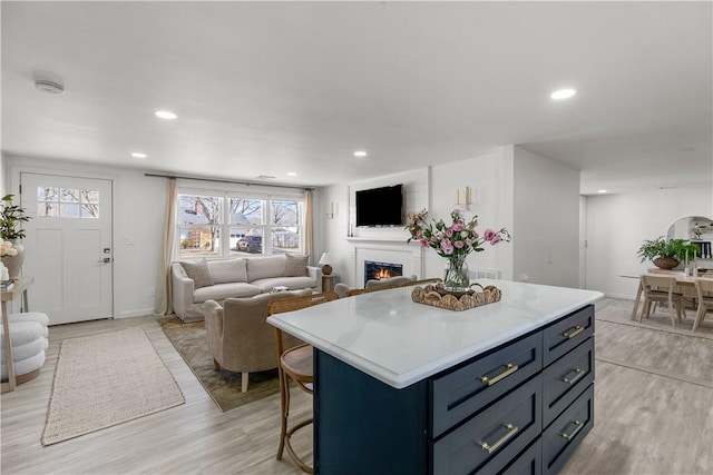 kitchen with open floor plan, a center island, light countertops, and a lit fireplace