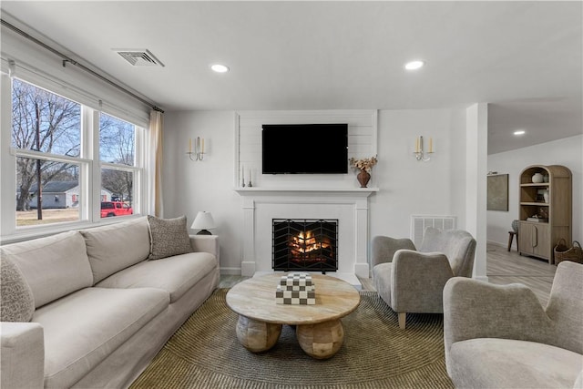 living area with recessed lighting, visible vents, a fireplace with flush hearth, and baseboards