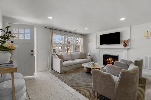 living area featuring recessed lighting, visible vents, and a lit fireplace