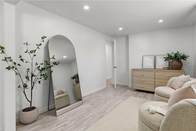 living area with recessed lighting, arched walkways, light wood finished floors, and baseboards