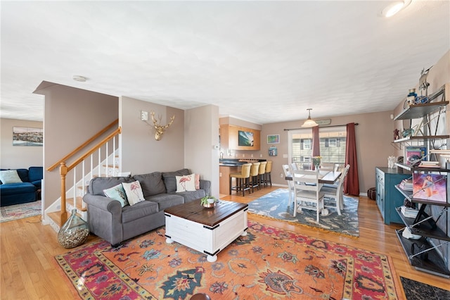 living room with stairway, baseboards, and light wood-type flooring