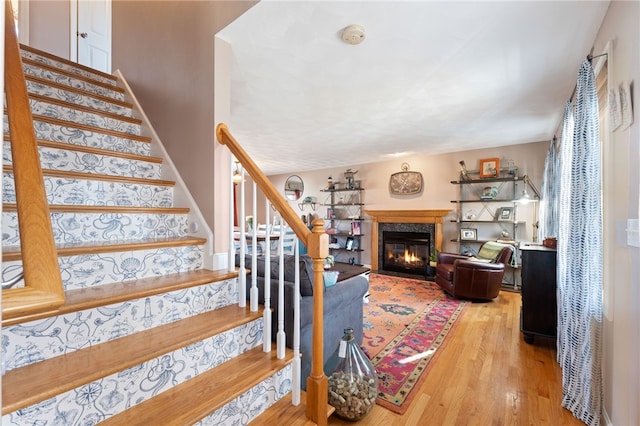 stairway with a premium fireplace, baseboards, and wood finished floors