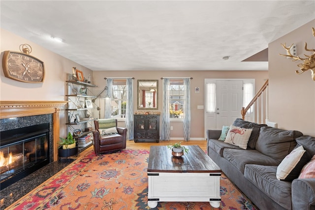 living room with stairs, baseboards, and a premium fireplace