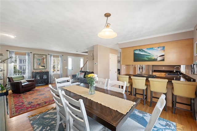 dining space featuring light wood finished floors, stairs, and ornamental molding