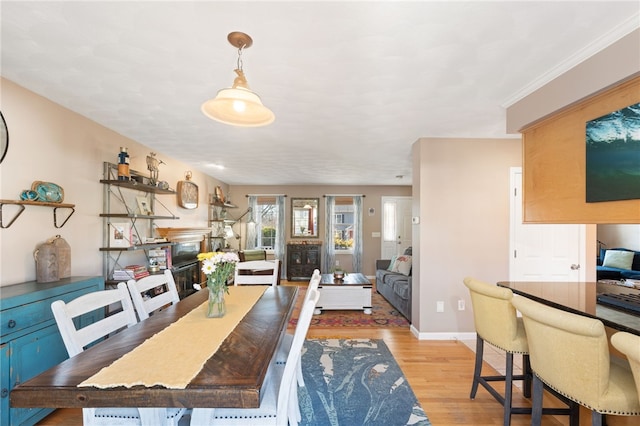 dining area featuring baseboards, ornamental molding, and light wood finished floors