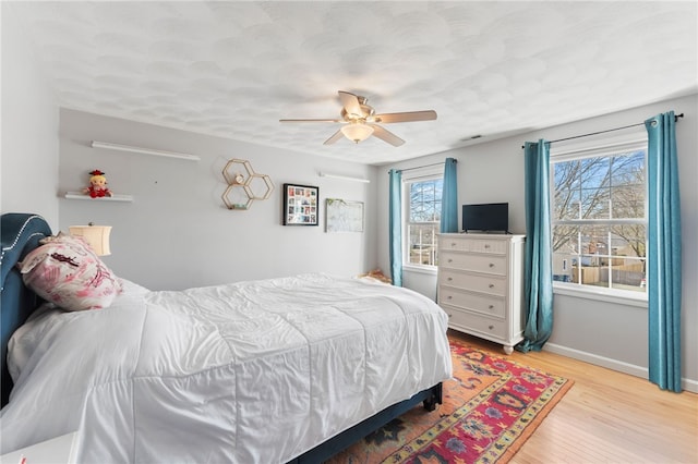 bedroom with visible vents, multiple windows, wood finished floors, and baseboards